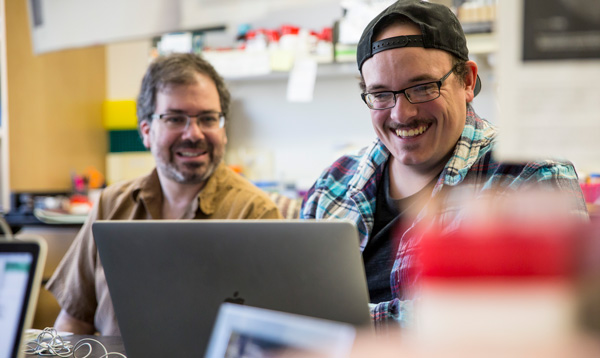 A faculty member working with a student at a computer.