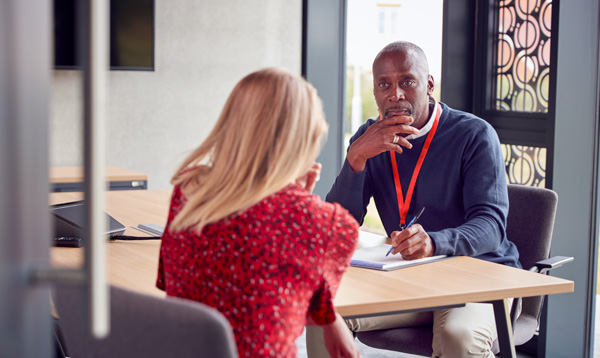 A teacher sitting at his desk receiving consultation.